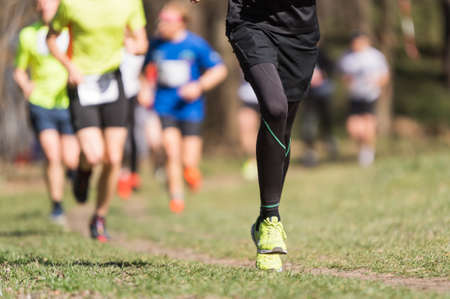 Marathon running race, people feet on grass roadの写真素材