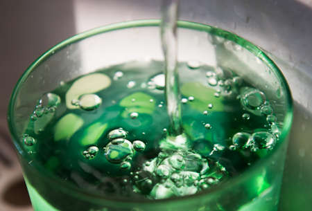 A glass of pure fresh water is poured into a glass from coolerの写真素材