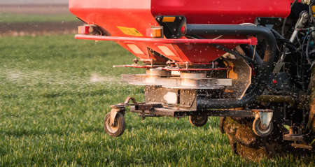 Farmer with tractor seeding - sowing crops at agricultural fields in springの写真素材