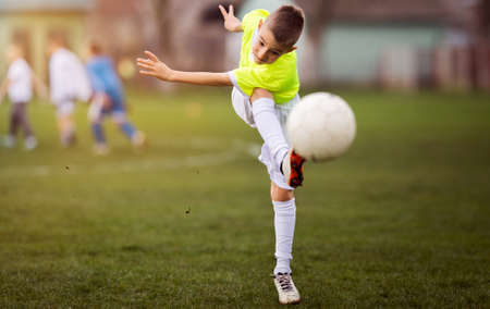 Boy kicking football on the sports field during soccer matchの写真素材