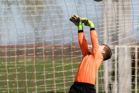 Young Boy Goalkeeper Saving A Football In A Game Of Soccer.の写真素材