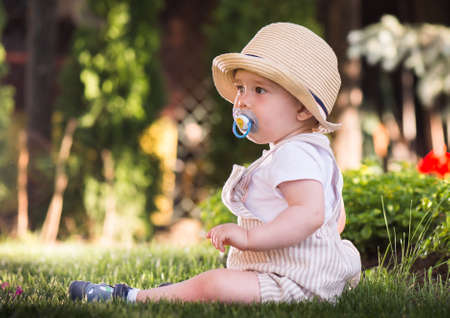 Baby boy sitting on the grass  watching flowers in the garden on beautiful spring dayの写真素材