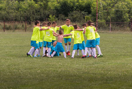 Kids soccer football - young children players celebrating in hug after victoryの写真素材