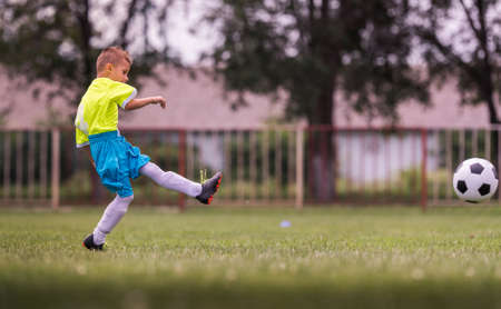 Boy kicking football on the sports field during soccer matchの写真素材