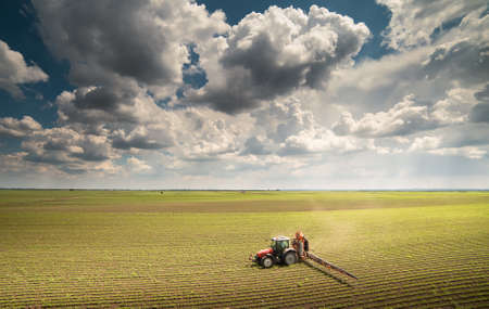 Tractor spraying pesticides on soybean field with sprayer at springの写真素材