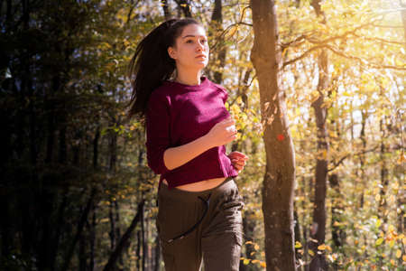 Beautiful girl running trough forest in autumn