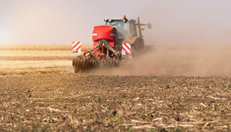Farmer with tractor seeding  crops at agricultural fieldの写真素材