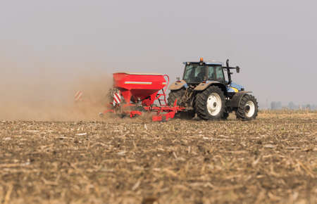 Farmer with tractor seeding  crops at agricultural field
