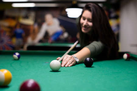 Pretty smiling girl playing billiard
