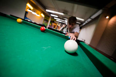 Handsome young guy playing billiards at game center