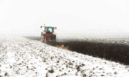 Tractor plowing a field in winterの写真素材