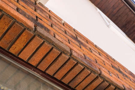 Worker putting red bricks on the house walls