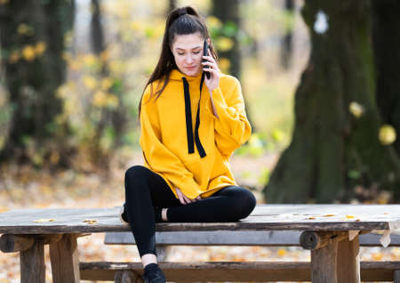 Beautiful young girl in the nature using her mobileの写真素材