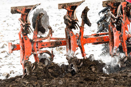 Tractors plowing stubble fields during winterの写真素材