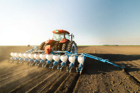  Farmer with tractor seeding  crops at agricultural field