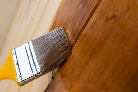 Painting teak wooden surface with a paintbrushの写真素材