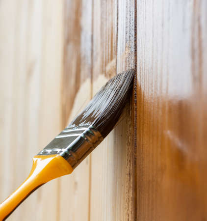 Painting teak wooden surface with a paintbrushの写真素材