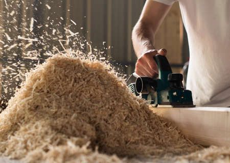 Carpenter works with electrical planer in workshopの写真素材