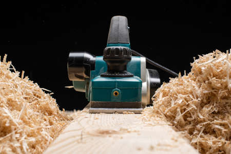 Isolated ectrical planer near bunch of sawdust in workshop