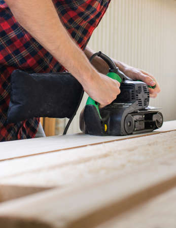 carpenter works with belt sander in carpentry