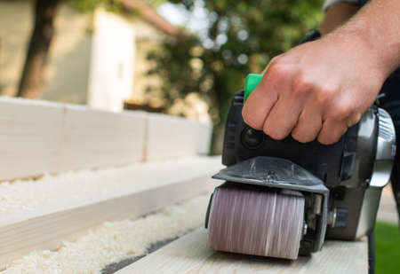 carpenter works with belt sander in carpentryの写真素材