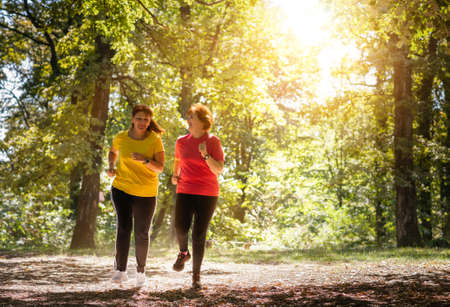 Two middle aged women running through a forestの写真素材
