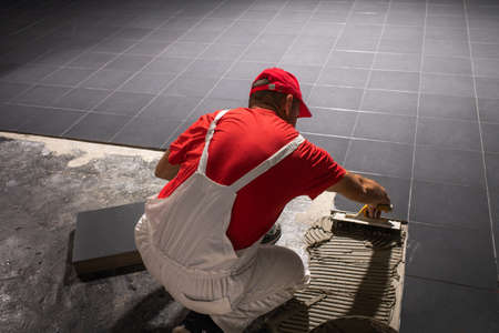 A construction worker putting on new floor tiles.の写真素材