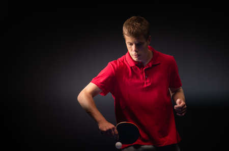 Young man playing table tennis on black studio background.の写真素材