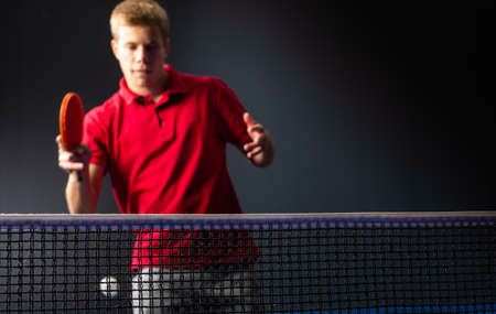 Young man playing table tennis on black studio background.の写真素材