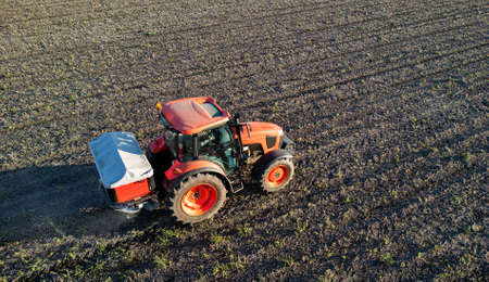 Tractor spreading artificial fertilizers  in field