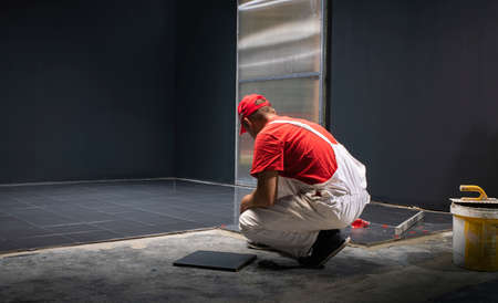 A construction worker putting on new floor tiles.の写真素材