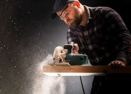 Construction worker crosses a board with a circular saw.