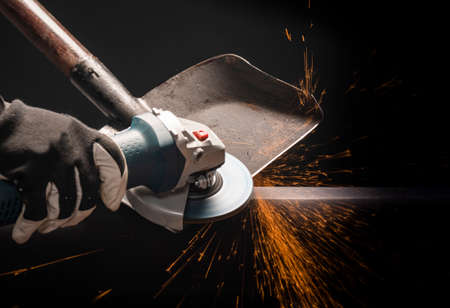 Sharpening garden shovel blade with electric angle grinder indoor