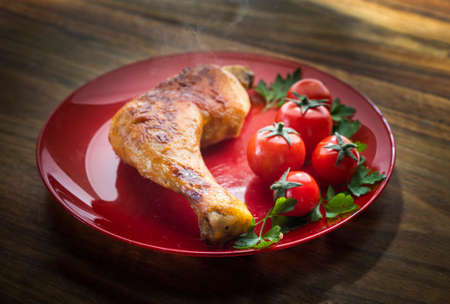 Roasted chicken leg with cherry tomato.Top view.
