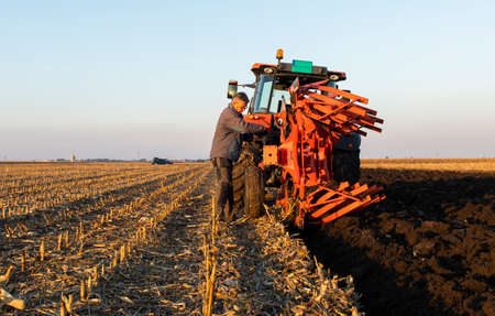Mechanic fixing plow on the tractor. Improvement, work.