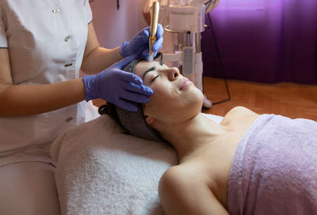 Beautician performs a  treatment on a woman s face