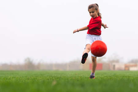 Girl kicks a soccer ball on a soccer fieldの写真素材