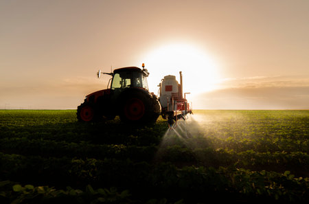 Tractor spraying pesticides on soy field  with sprayer at spring