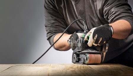 Carpenter works with belt sander in carpentryの写真素材