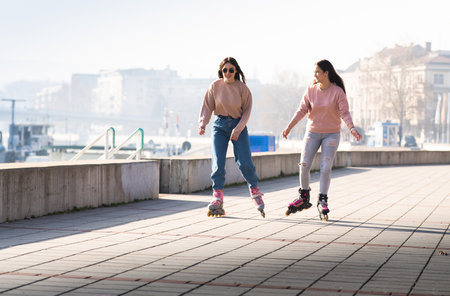 Two cute teenage girls on roller skates having fun in urban environment.の写真素材