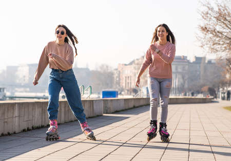 Two cute teenage girls on roller skates having fun in urban environment.の写真素材