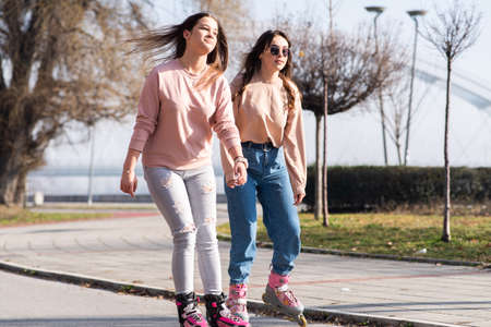Two cute teenage girls on roller skates having fun in urban environment.の写真素材