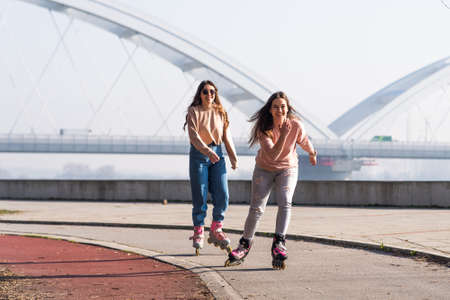 Two cute teenage girls on roller skates having fun in urban environment.の写真素材