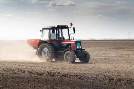 Tractor spreading artificial fertilizers  in field