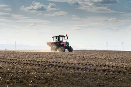 Tractor spreading artificial fertilizers  in field