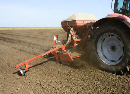 Farmer with tractor seeding crops in the field.の写真素材