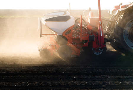 Farmer with tractor seeding - sowing crops at agricultural field. Plants, wheat.の写真素材