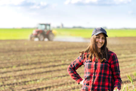Young pretty farmer girl standing in  of green wheat field
