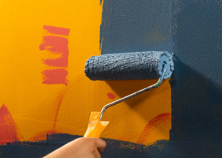 Wet blue paint on a wall, with a hand, holding a paint rollerの写真素材