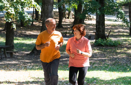 Happy senior couple running together in the parkの写真素材